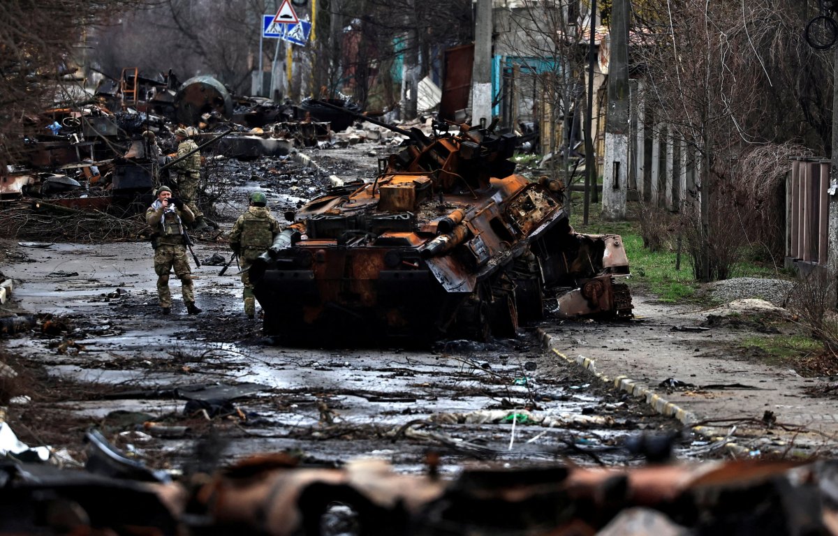 A soldier takes a photograph of his comrade as he poses beside a destroyed Russian tank and armoured vehicles, amid Russia’s invasion on Ukraine in Bucha, in Kyiv region