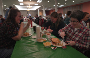 From left, Laura Kuster, Miranda Crotsley, and Hollen Barmer eat fish sandwiches, homemade perogies, and macaroni and cheese at the St. Maximilian Kolbe Catholic Church fish fry in the West Homestead neighborhood of Pittsburgh, on Friday, Feb. 24, 2023.