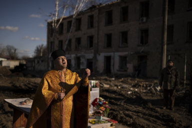 A priest performs a religious service on the place of a building that was demolished after being heavily damaged by an airstrike, one year ago, in memory of those killed in Borodyanka, Ukraine, Thursday, March 2, 2023