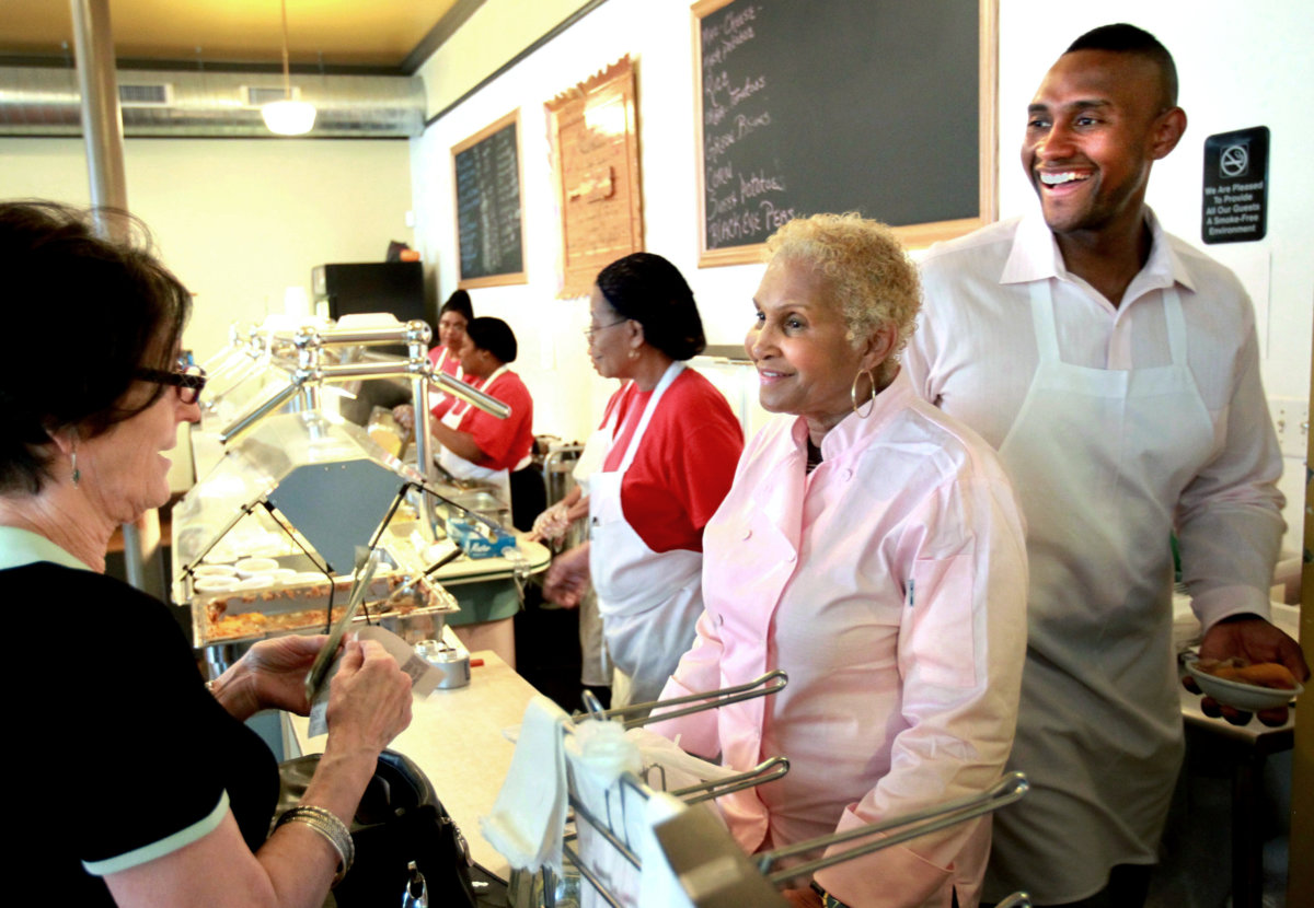 A customer picks up some food to-go from Sweetie Pie's owner Robbie Montgomery, center, and Montgomery's son, James "Tim" Norman, right, at Sweetie Pie's in St. Louis, April 19, 2011.