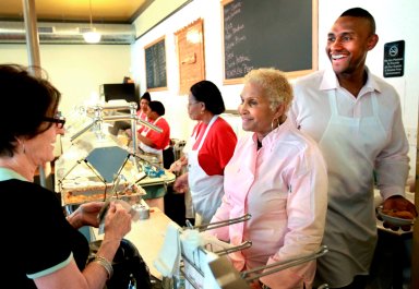 A customer picks up some food to-go from Sweetie Pie's owner Robbie Montgomery, center, and Montgomery's son, James "Tim" Norman, right, at Sweetie Pie's in St. Louis, April 19, 2011.