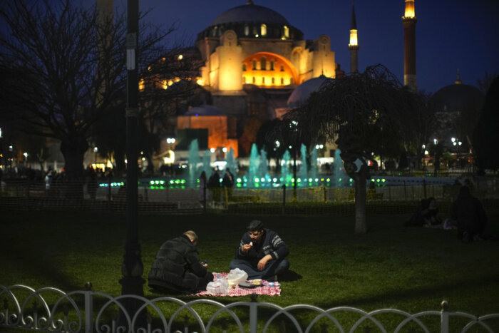 People break their fast after dusk on the first day of Ramadan backdropped by the iconic Byzantine-era Hagia Sophia mosque in Istanbul, Turkey.