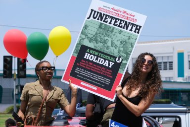 People hold a sign in their car during a car parade to mark Juneteenth on June 19, 2021, in Inglewood, Calif. Communities all over the country will be marking Juneteenth,